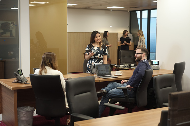 Clients interacting and working in a warm, professional coworking space with private booths and city views.