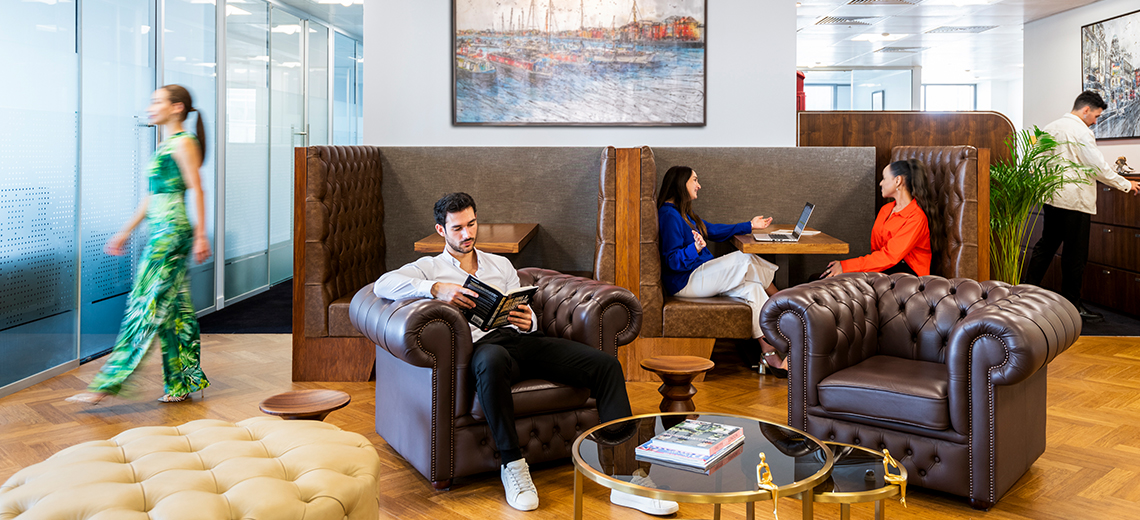 Clients working and networking in Canary Wharf coworking space featuring 5-star interiors, hot desks, and collaborative booths.