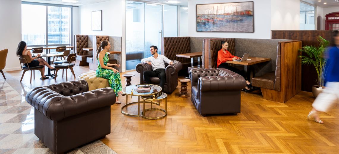 Clients working and networking in Canary Wharf coworking space featuring hot desks and collaborative booths.